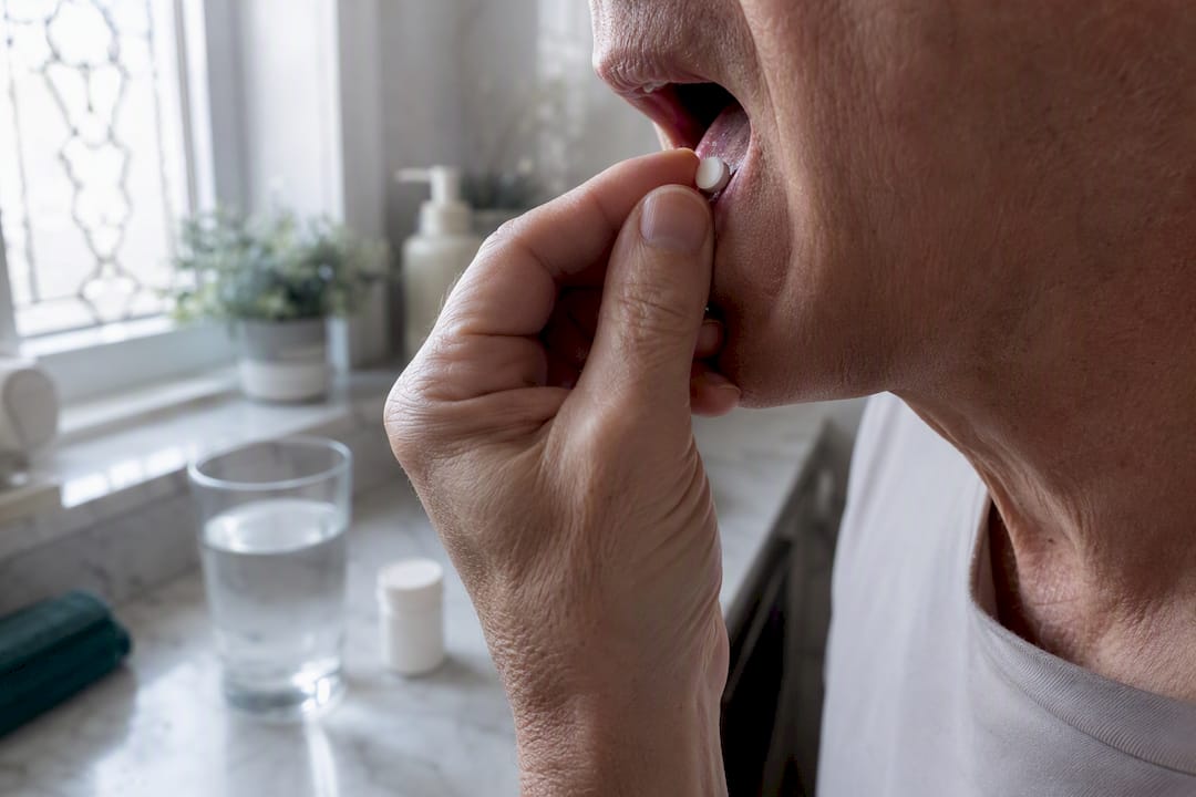 Hand placing NMN tablet under tongue